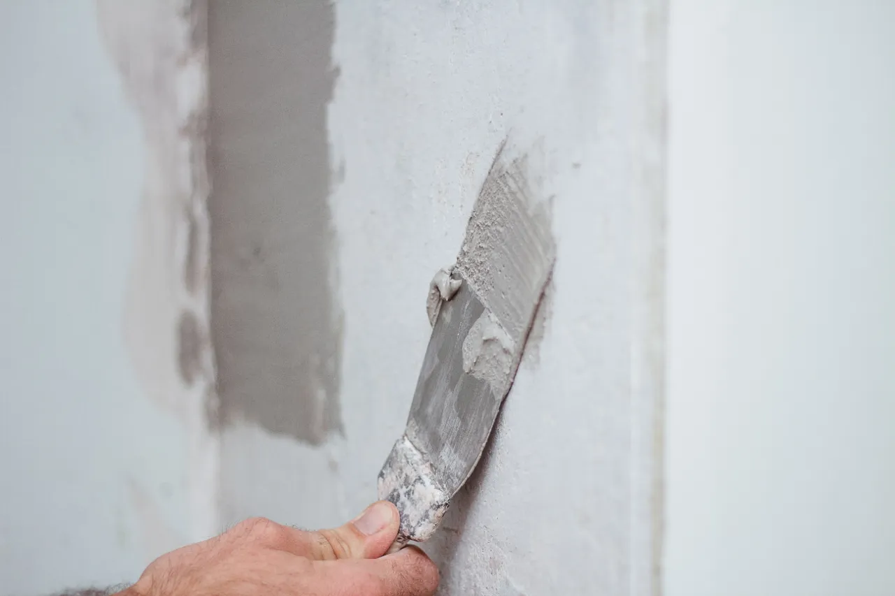 Wall patch with putty knife during drywall repair in New York