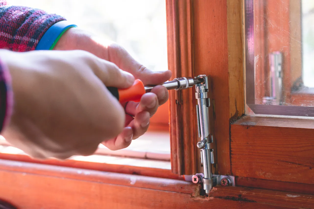 Window repair with screwdriver and hardware in New York